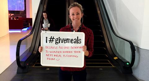 A volunteer holding a "i #givemeals" sign