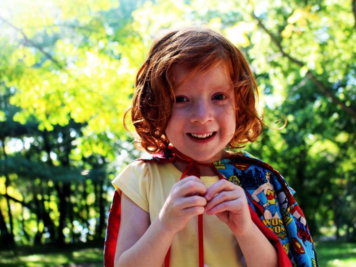 A kid wearing a superhero cape