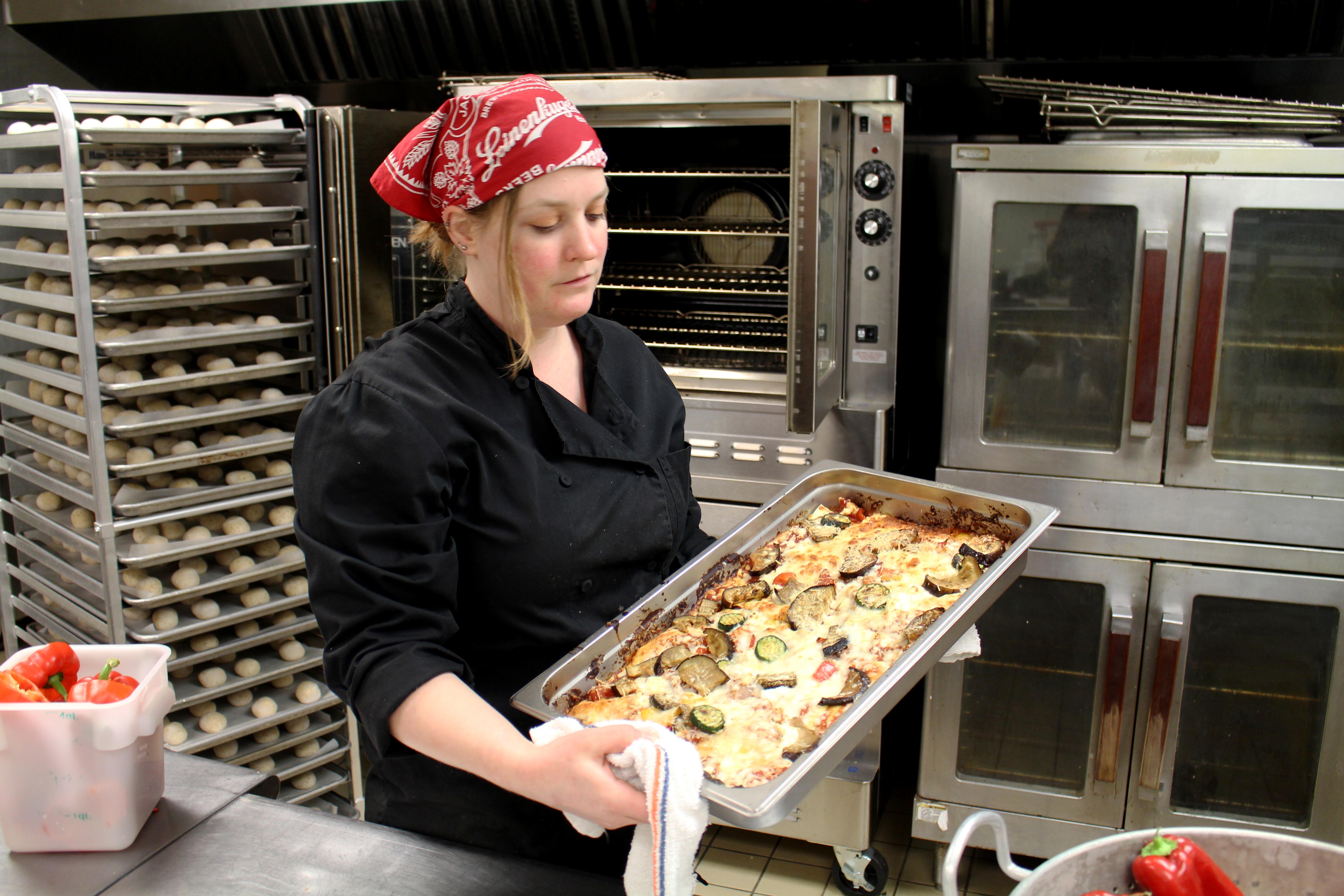 New Kitchen of Opportunities chef Michelle Spieker removes vegetable lasagna from oven
