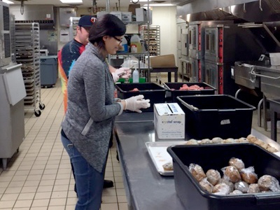 A Kitchen of Opportunities volunteer helps pack meals