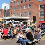 A food truck rally with people eating on picnic tables